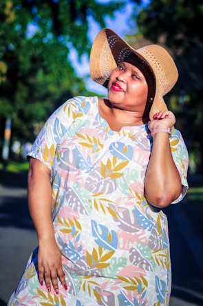 A model wearing a vibrant floral dress in a sunny park.