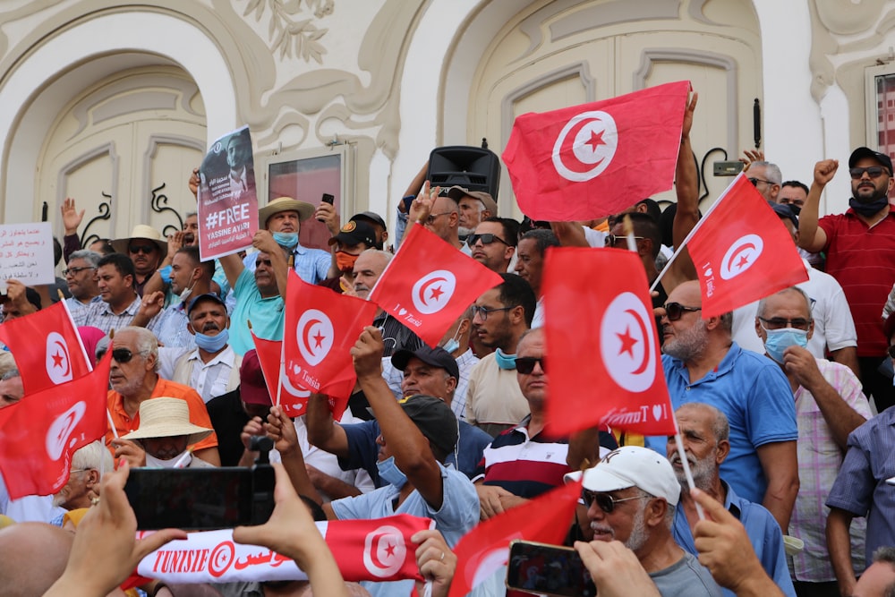 a large group of people holding flags in front of a building