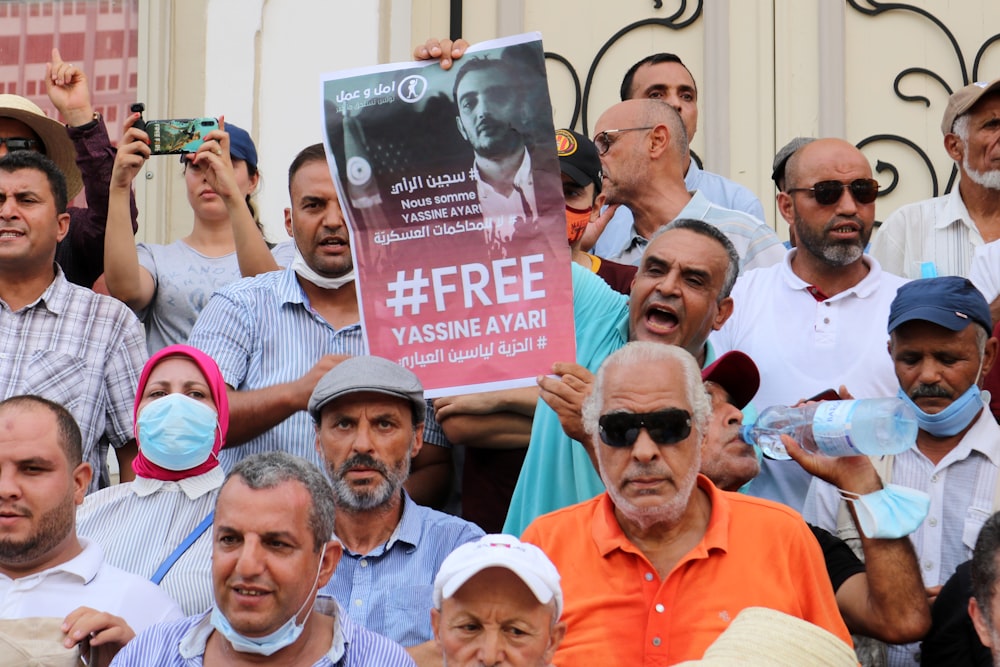 a group of people holding signs and wearing masks