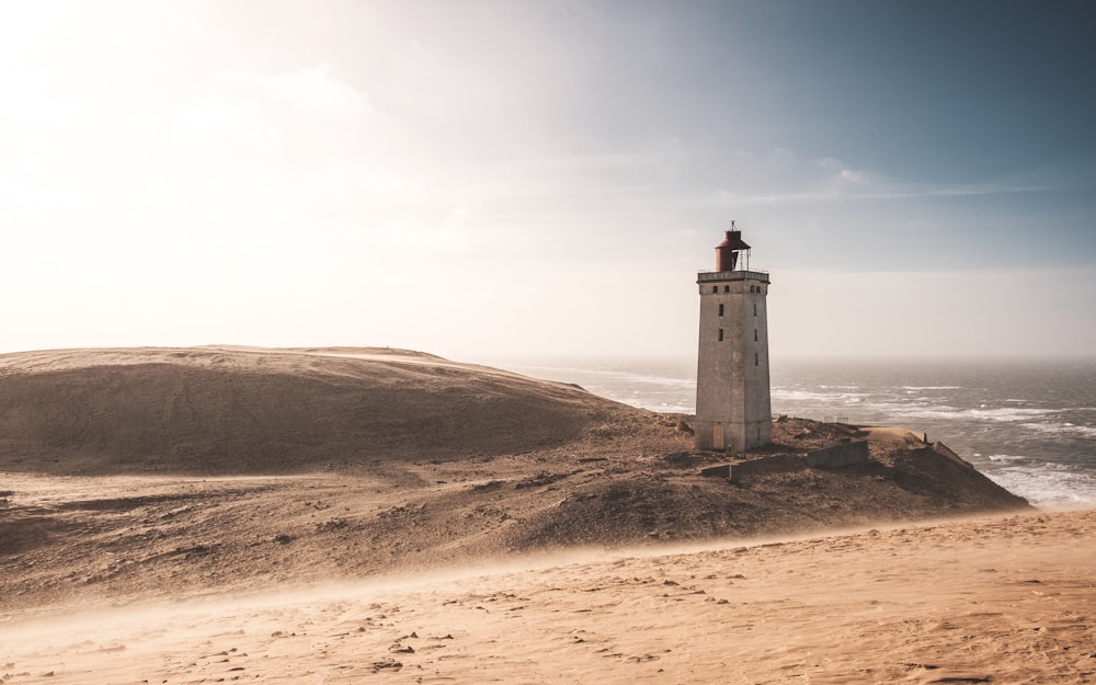 a light house sitting on top of a sandy hill
