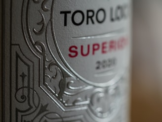 Close-up of a wine bottle label with intricate embossed patterns. The words 'Toro Loco' and 'Superior 2020' are prominently displayed. The label features a combination of serif and sans-serif font styles, enhancing its elegant appearance.