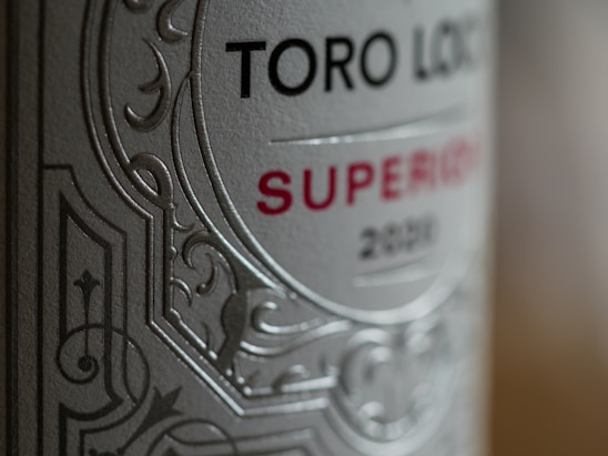 Close-up of a wine bottle label with intricate embossed patterns. The words 'Toro Loco' and 'Superior 2020' are prominently displayed. The label features a combination of serif and sans-serif font styles, enhancing its elegant appearance.