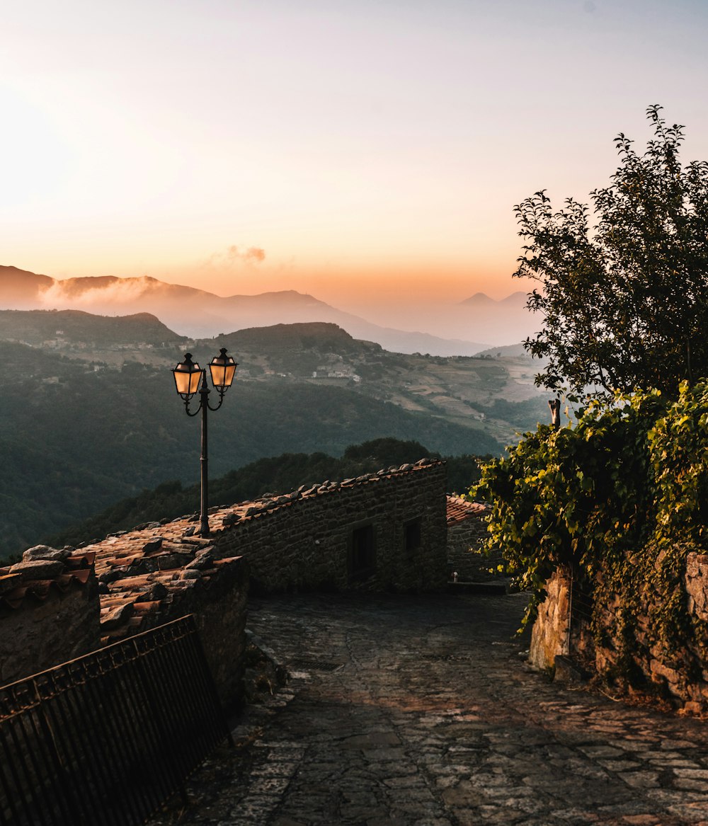 a street light sitting on the side of a stone road