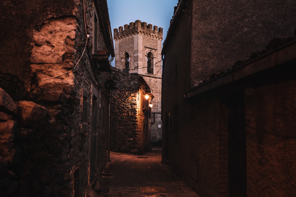 Un vicolo stretto con una torre dell'orologio sullo sfondo