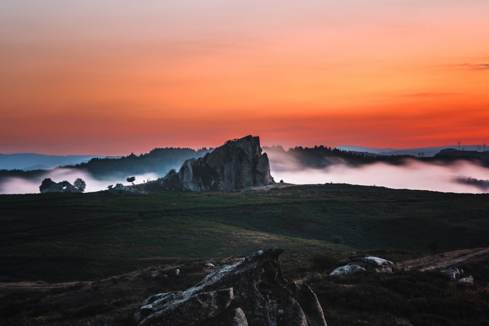 a mountain covered in fog at sunset