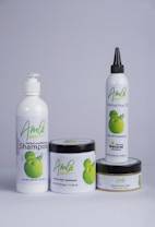 A set of four hair care products with white packaging, each featuring the word 'Amla' and an image of green fruit. The products include a herbal conditioning shampoo, herbal hair treatment, herbal hair oil, and herbal hair food.