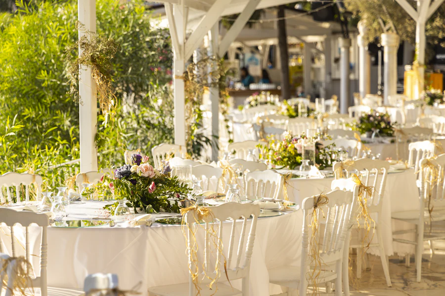 Mesas vestidas de blanco con flores bajo una pérgola