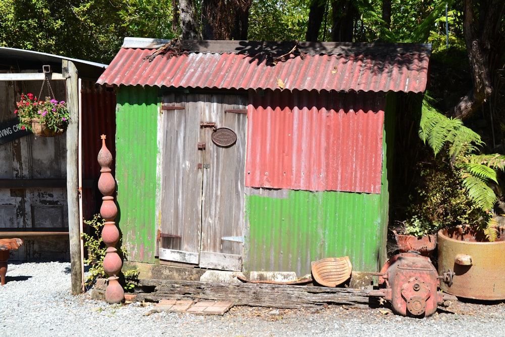 a green and red shed sitting next to potted plants