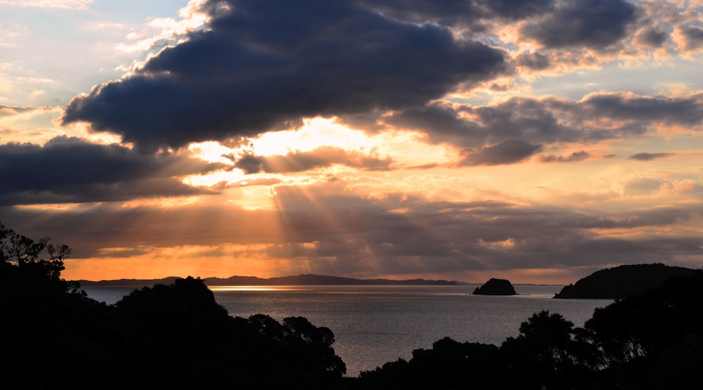 the sun is shining through the clouds over the water