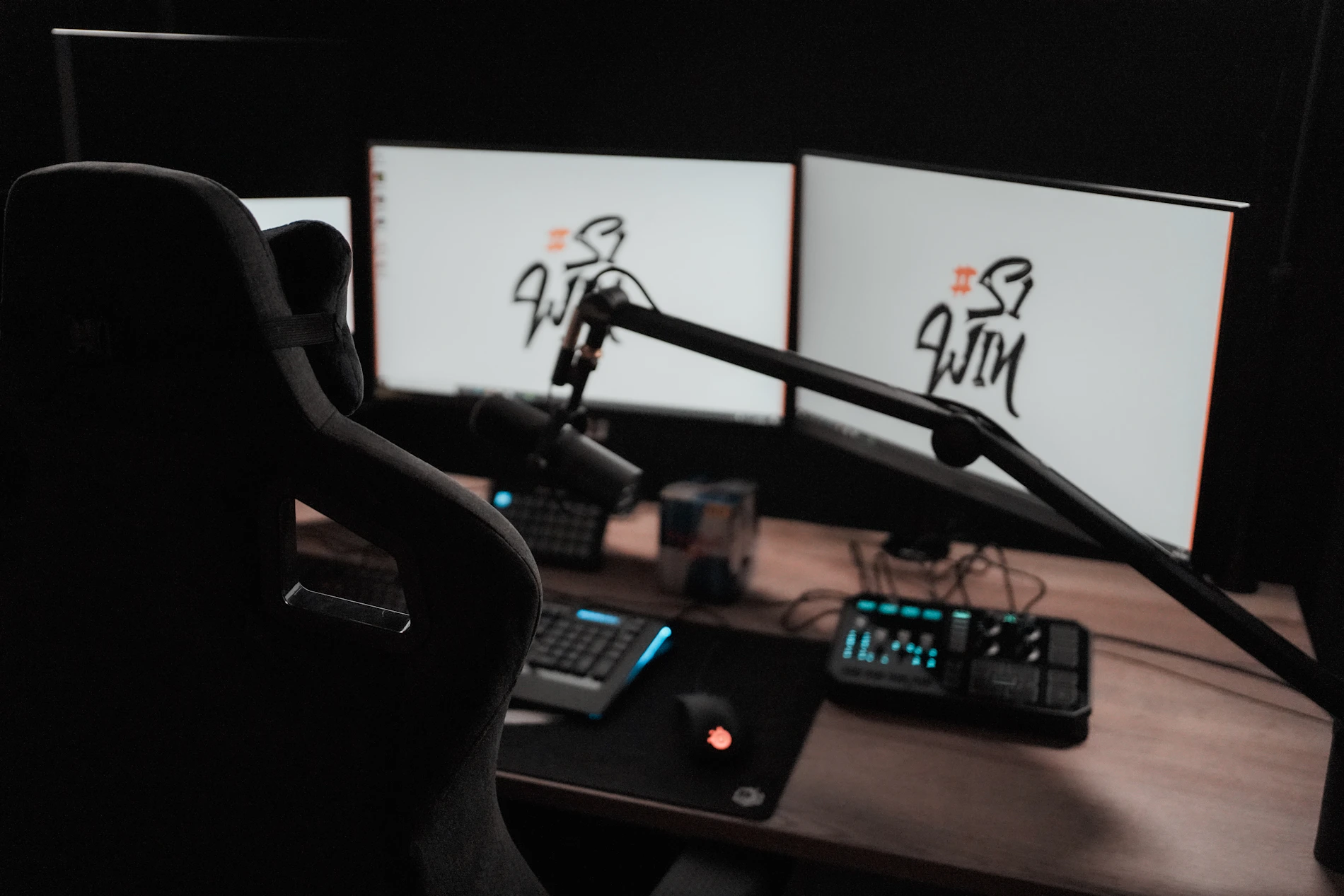Gaming streaming desk with microphone, gaming monitors, keyboard and illuminated gaming equipment
