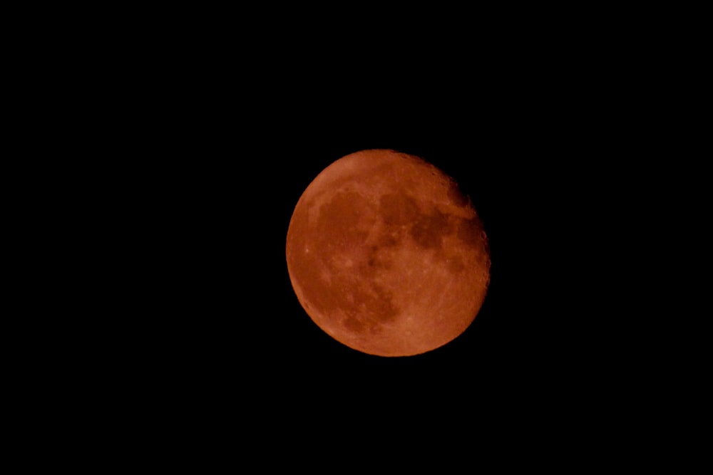 a red moon is seen in the dark sky