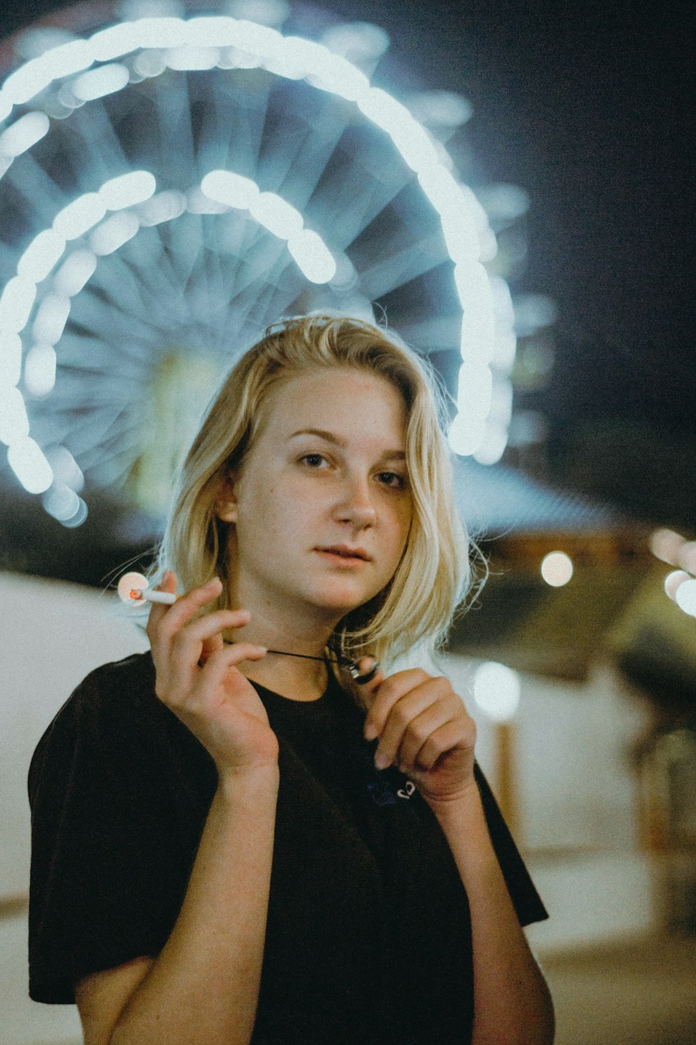 a woman standing in front of a ferris wheel at night