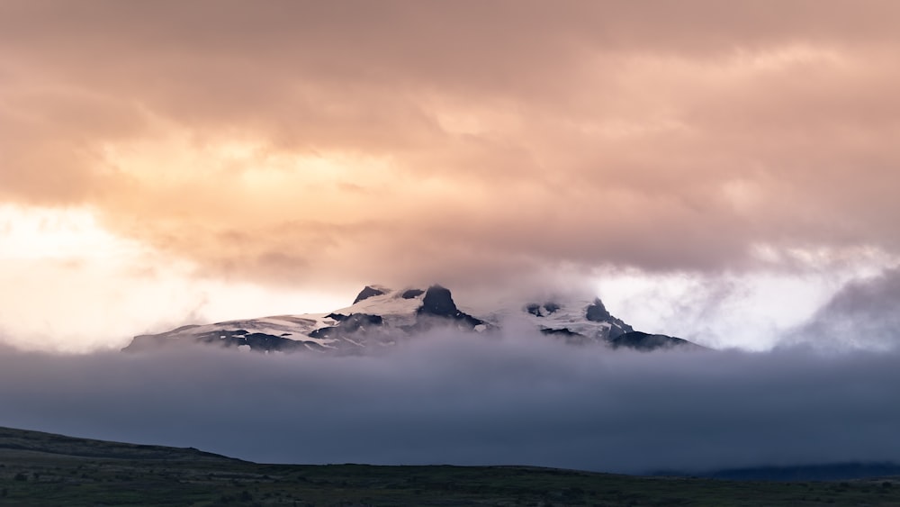 a large mountain covered in clouds in the distance