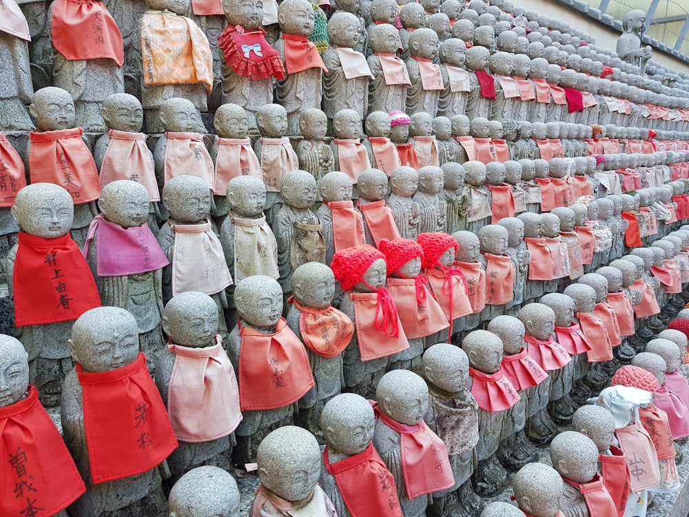 a wall of statues with red and pink scarves on them