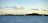 A serene sailboat gliding gently across Poole Harbour under a soft blue sky at sunset.