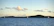 A serene sailboat gliding gently across Poole Harbour under a soft blue sky at sunset.