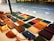 A display of various leather wallets arranged on a table, featuring different colors and styles. The table is situated outdoors with a tiled ground in the background.