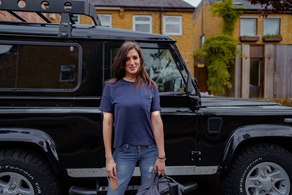 a woman standing in front of a black land rover