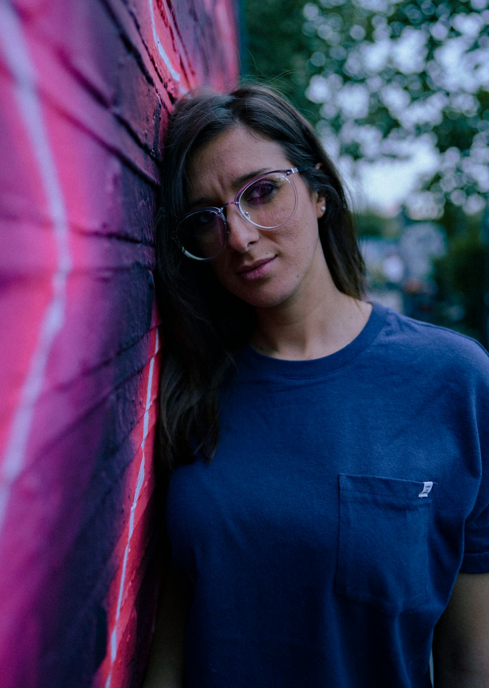 a woman wearing glasses leaning against a wall