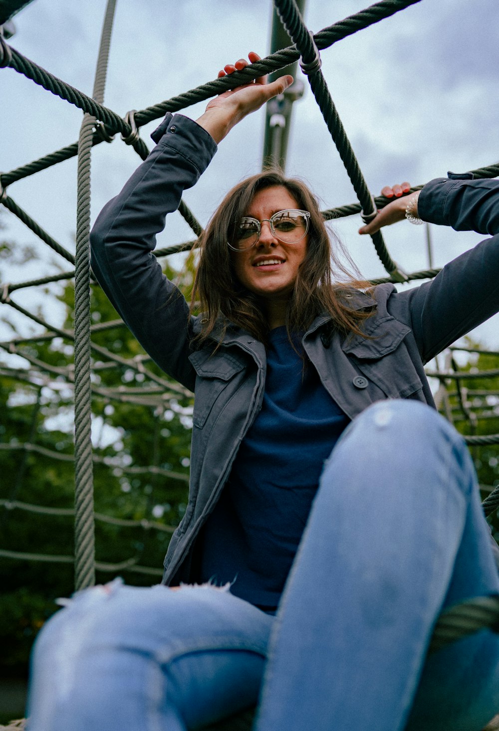 a woman sitting on top of a rope structure