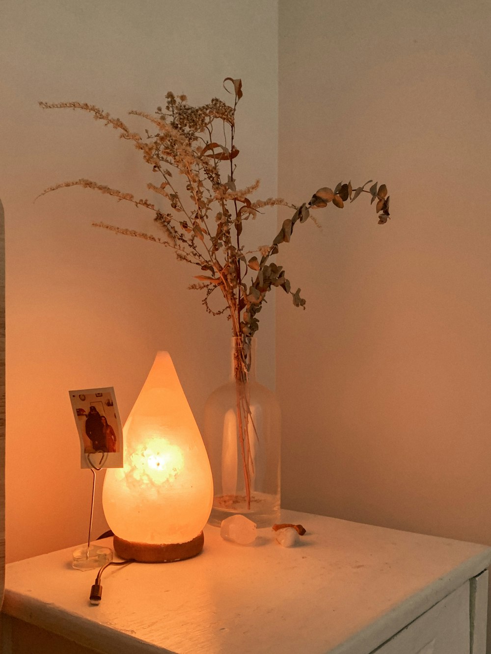 eine Vase mit Blumen und einer Kerze auf einem Tisch