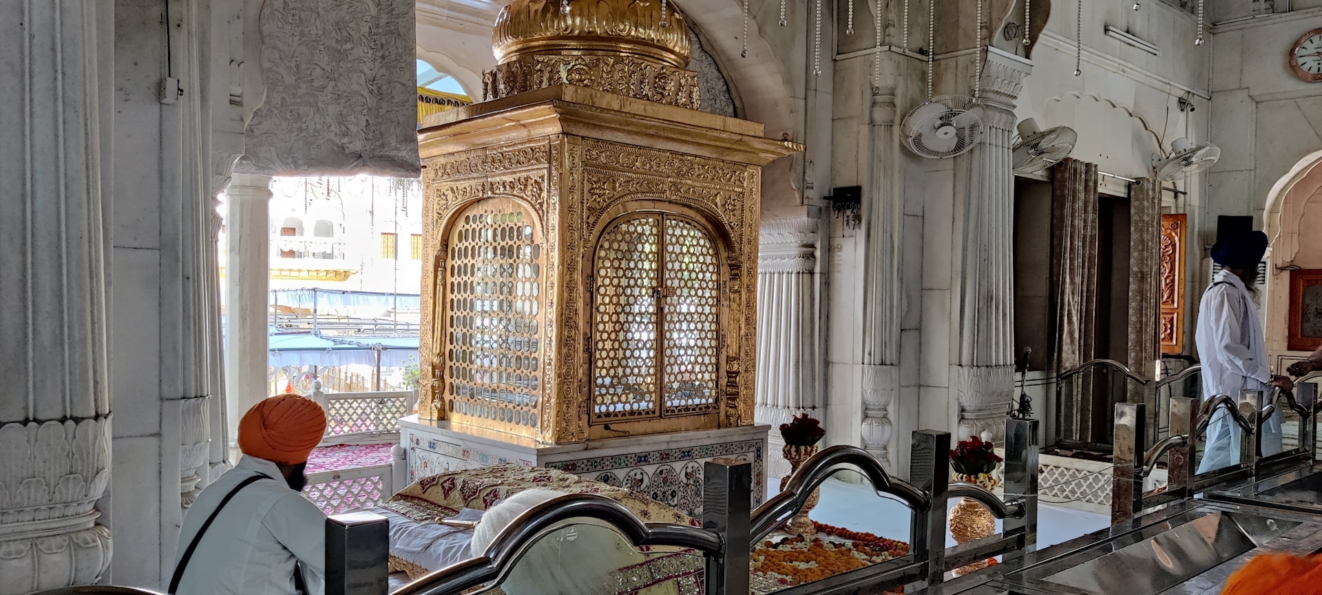Devotees gathered in quiet reflection inside the mandir, bathed in warm light filtering through stained glass windows, capturing the temple's tranquil spirit.