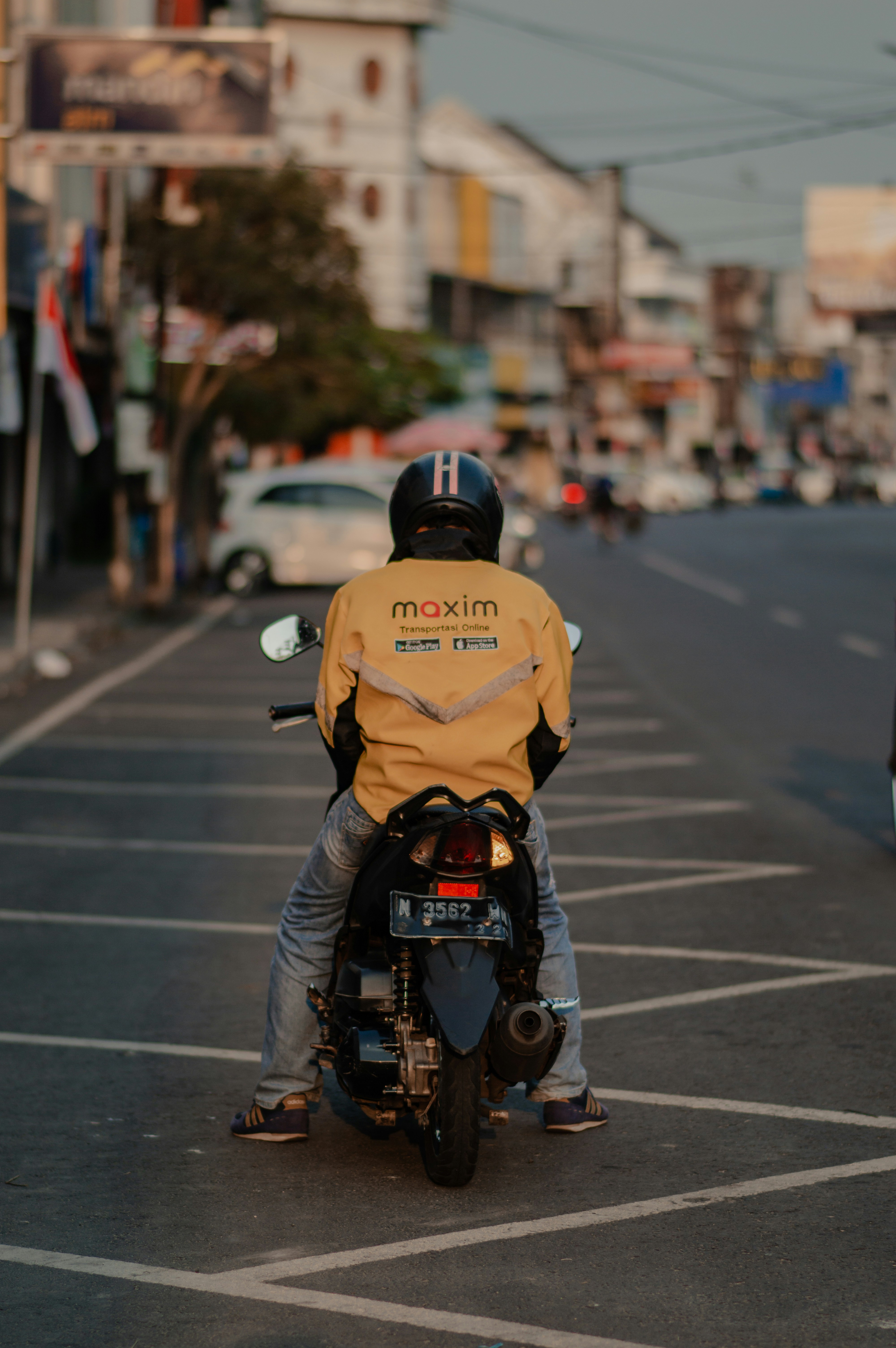 A man riding on the back of a motorcycle down a street photo – Free ...
