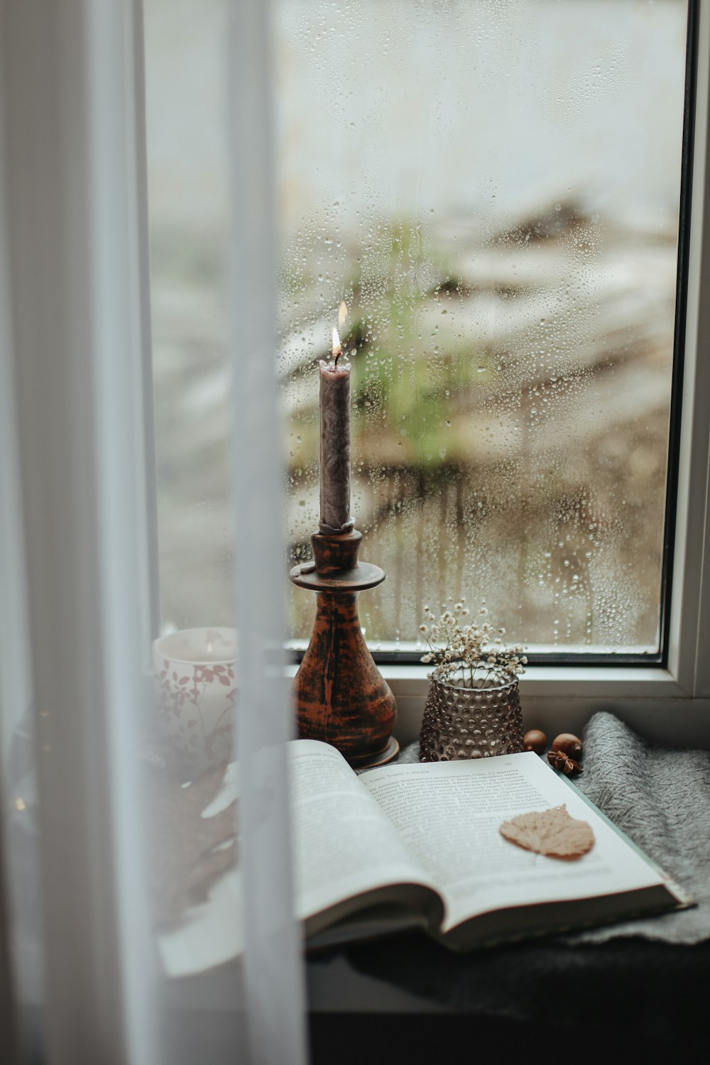 a candle and a book on a window sill