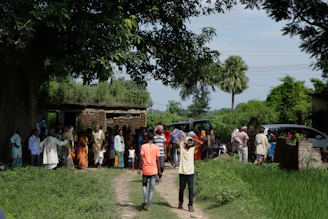 A group of villagers discussing plans under a large tree, showing collaboration.