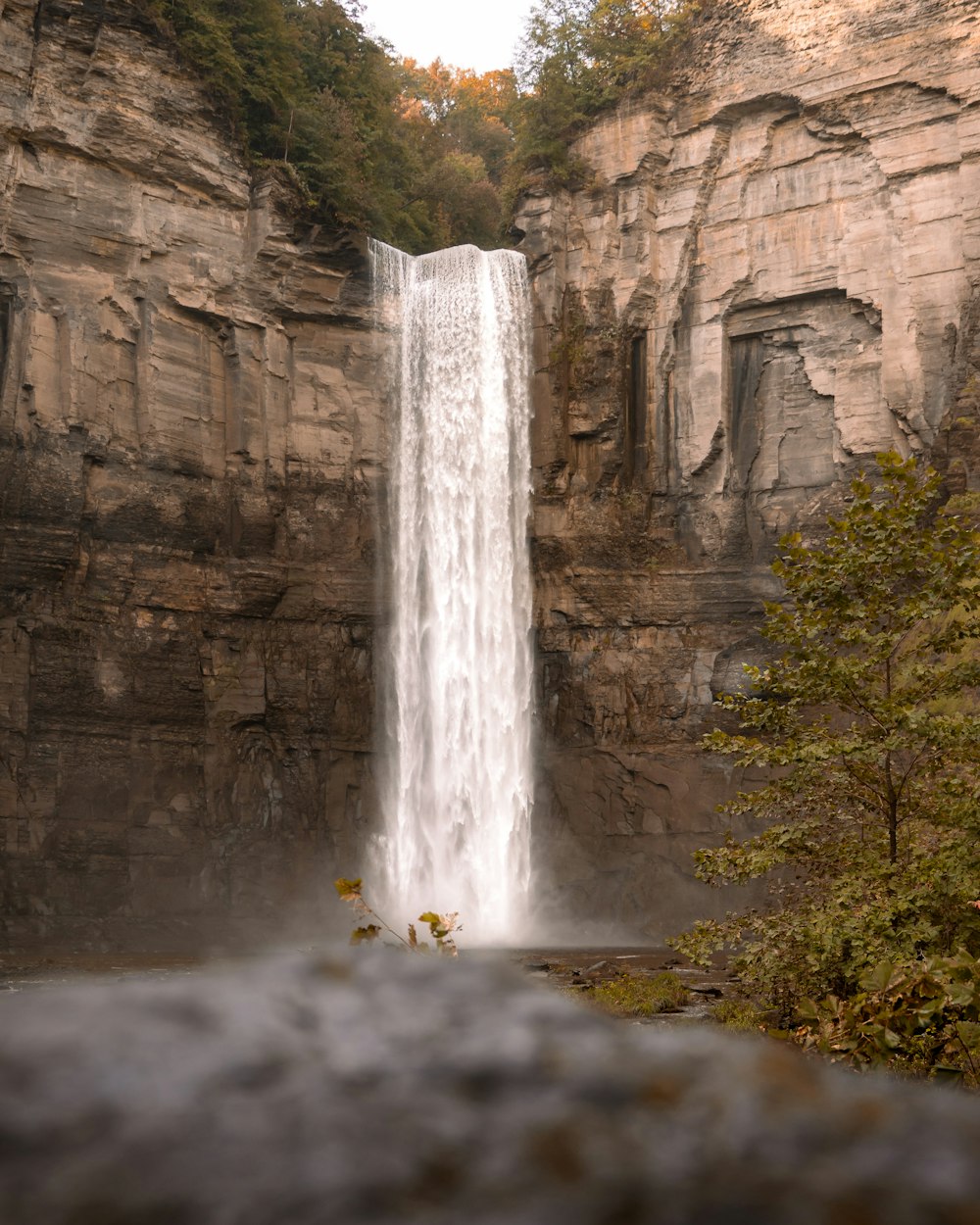 a large waterfall with a man standing in front of it