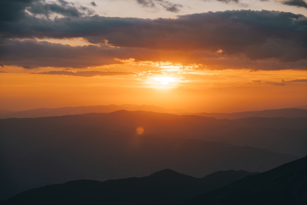 the sun is setting over a mountain range