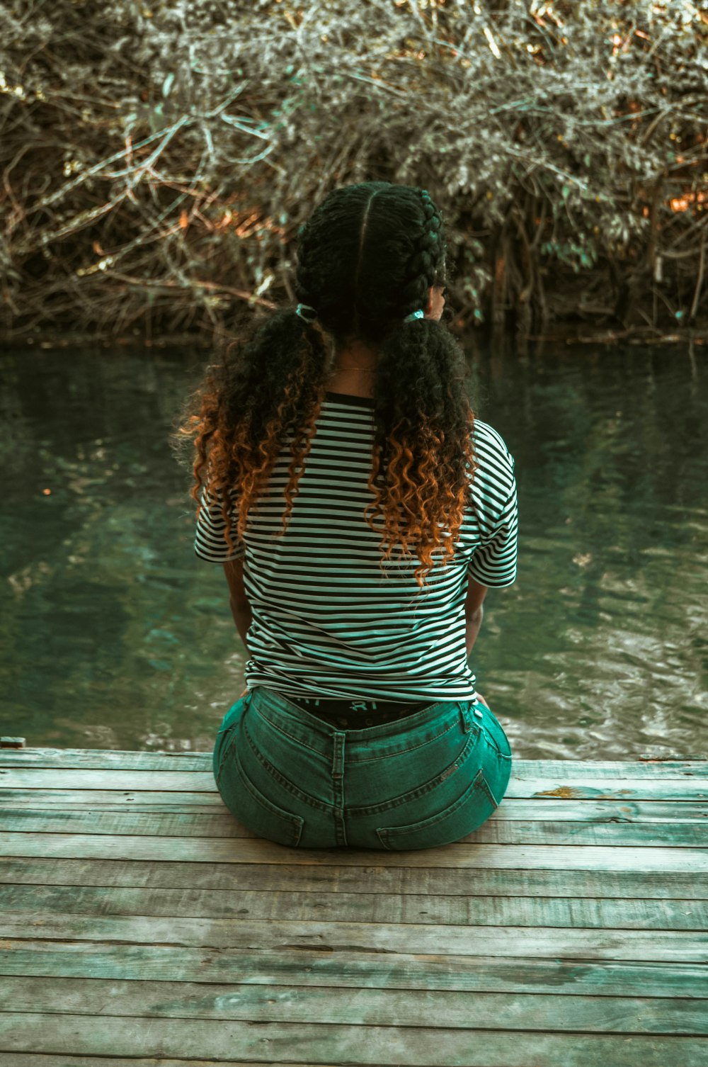 a woman sitting on a dock looking at the water