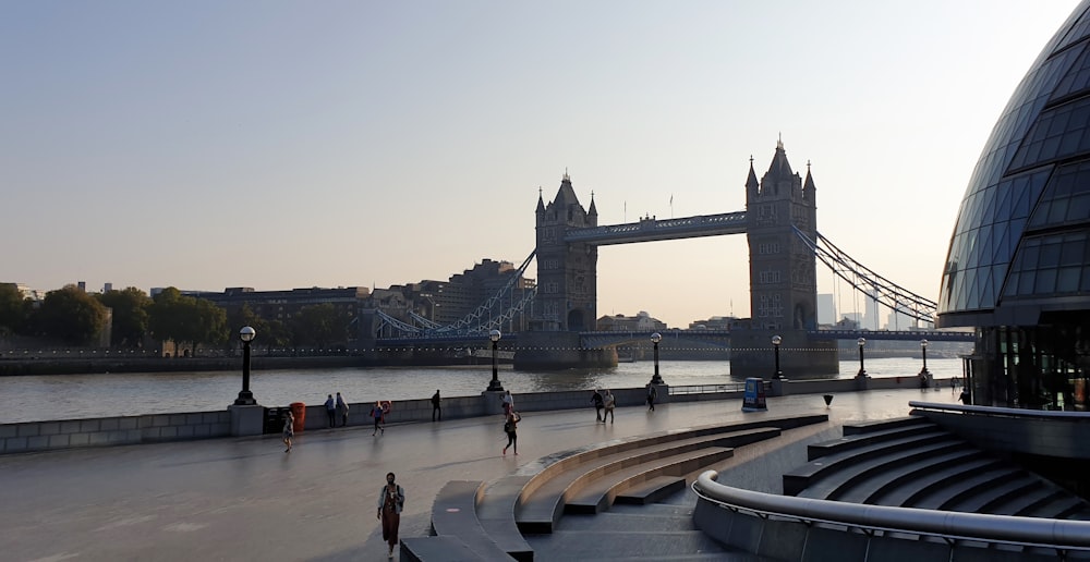 a group of people walking across a bridge next to a river