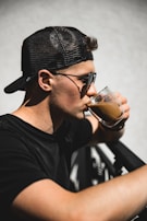 A sunny outdoor scene featuring someone wearing a Printvibe cap and sipping coffee.