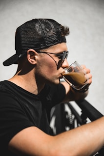 A sunny outdoor scene featuring someone wearing a Printvibe cap and sipping coffee.