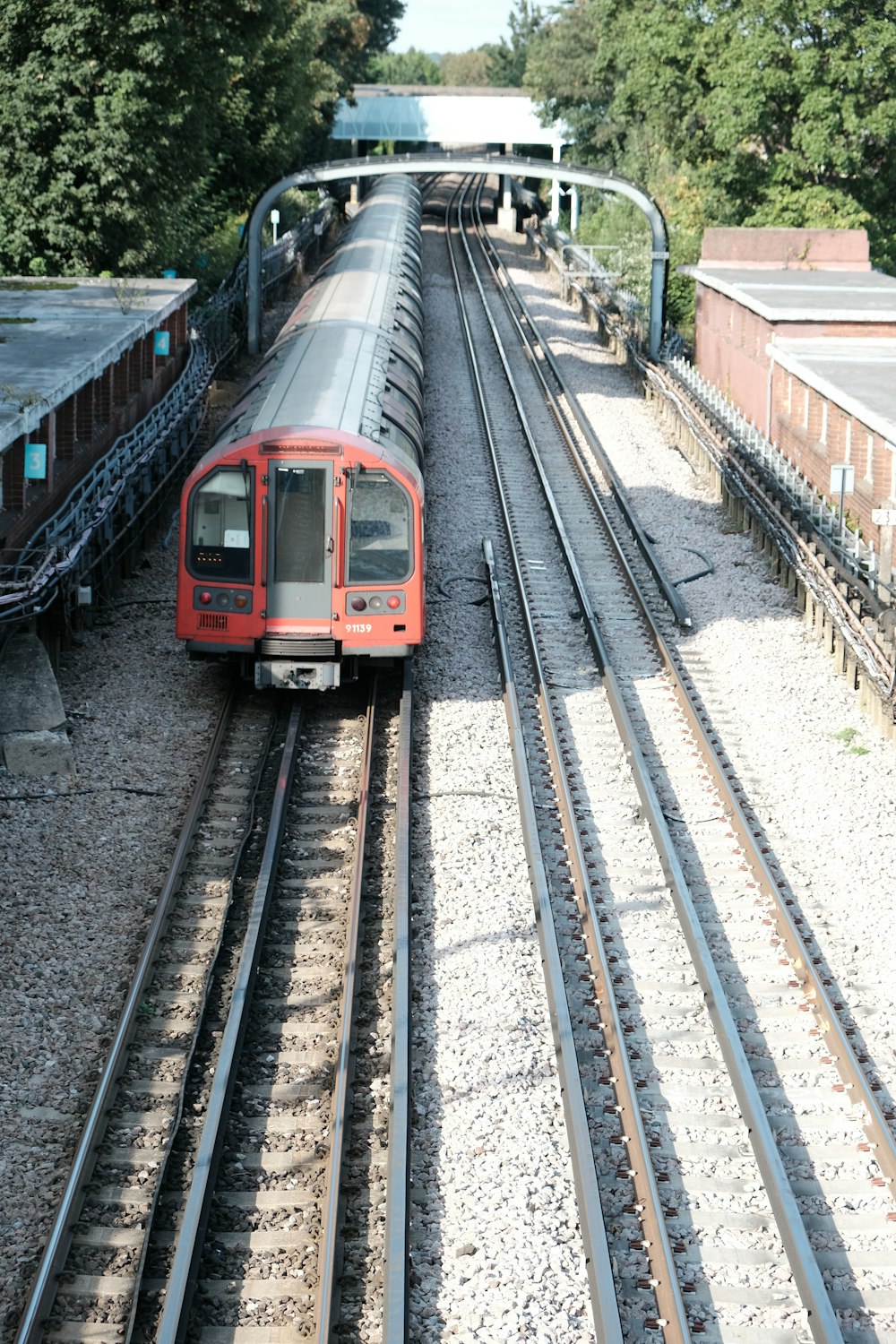 a red train traveling down train tracks next to a forest