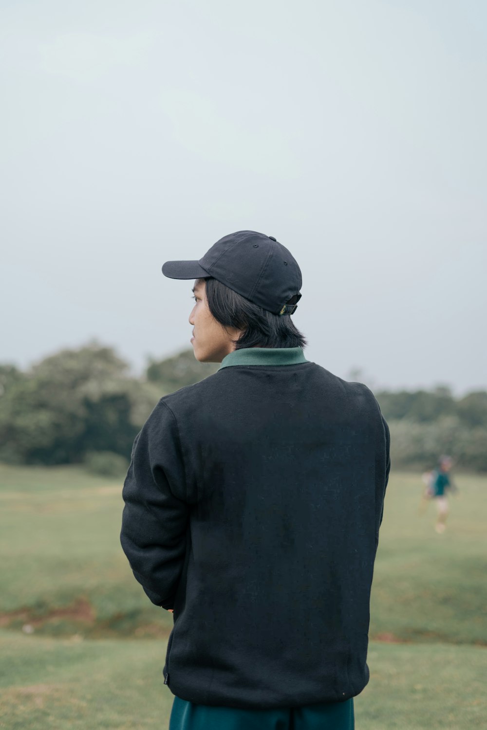 une personne debout dans un champ avec une casquette de baseball