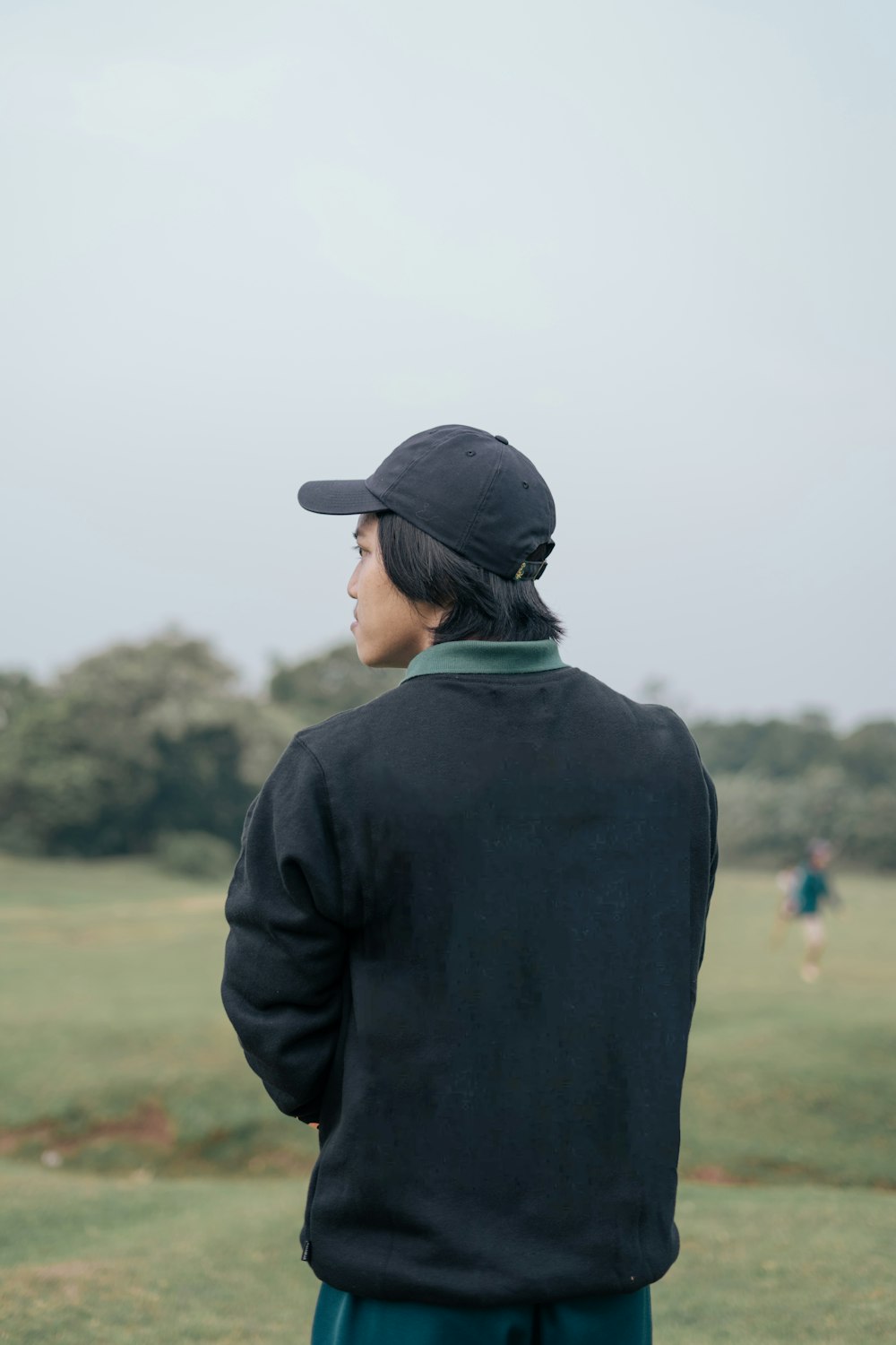 a person standing in a field with a baseball cap on