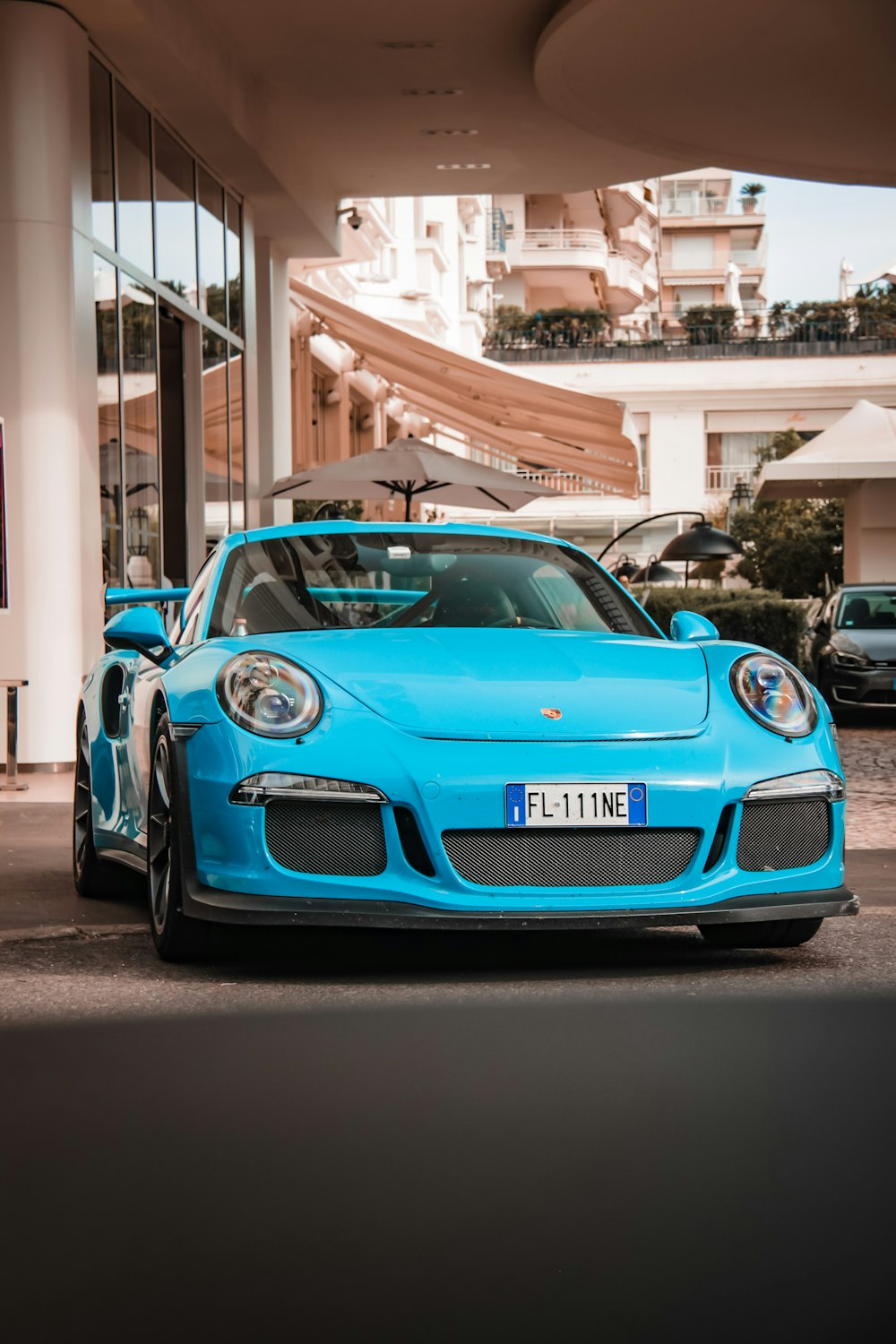 a blue sports car parked in front of a building