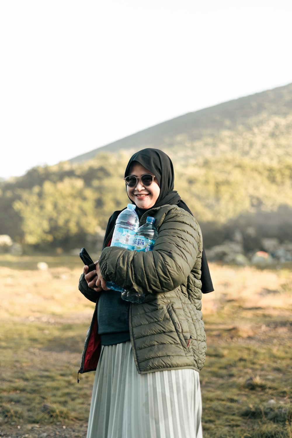 a woman standing in a field holding a bottle of water