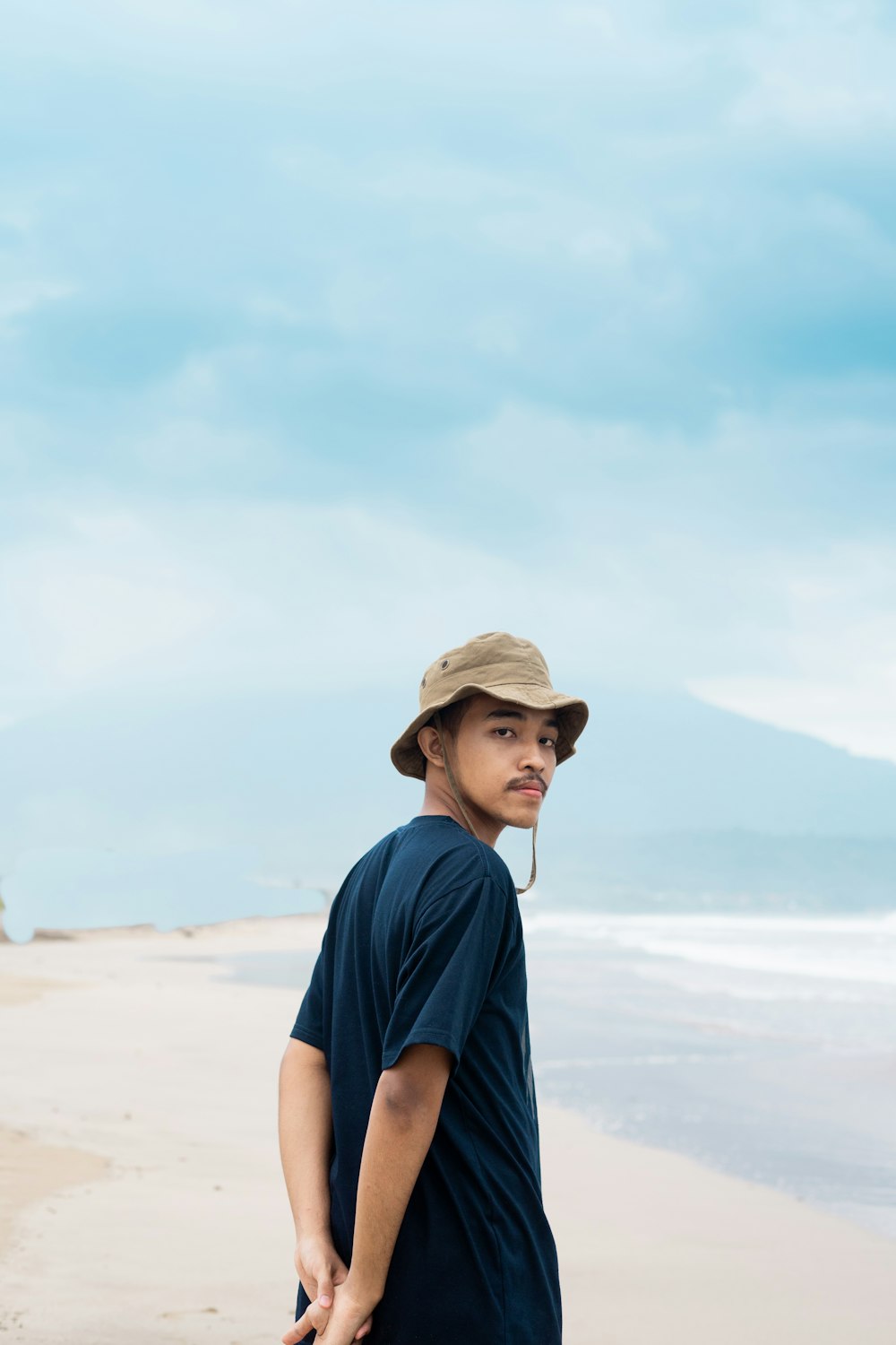 um homem em pé no topo de uma praia de areia