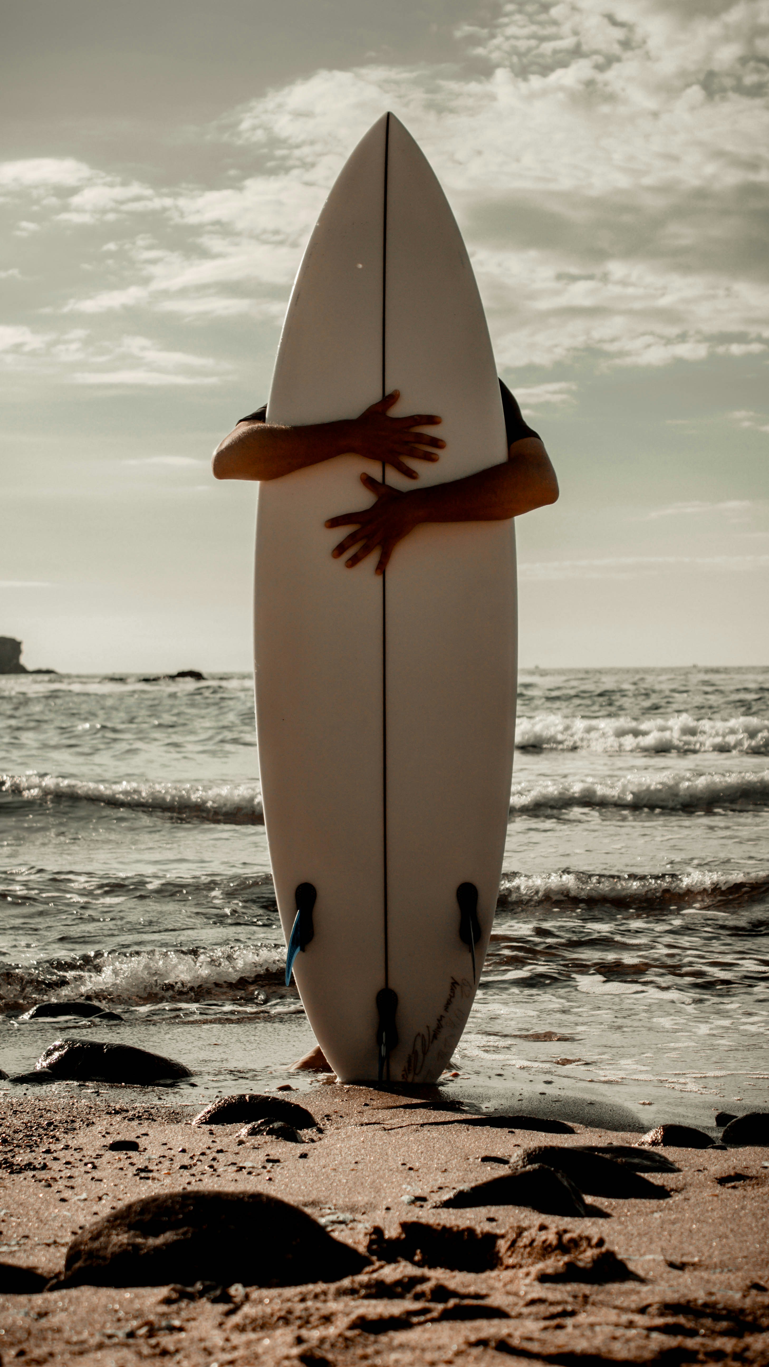 une planche de surf blanche posée au sommet d’une plage de sable