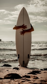 a white surfboard sitting on top of a sandy beach