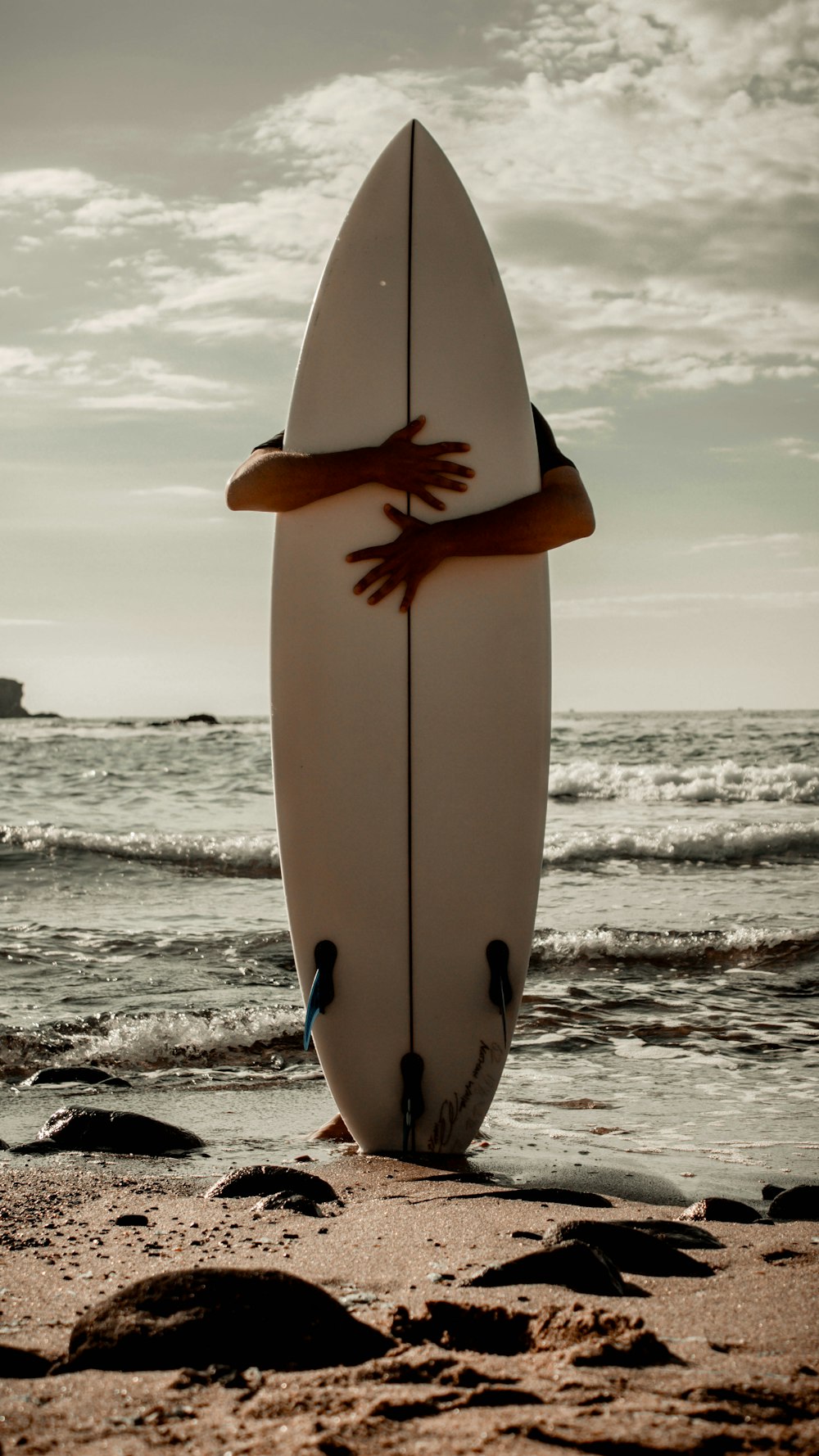 a white surfboard sitting on top of a sandy beach