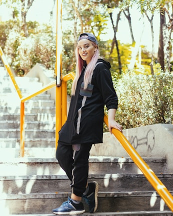a woman with pink hair is standing on some stairs