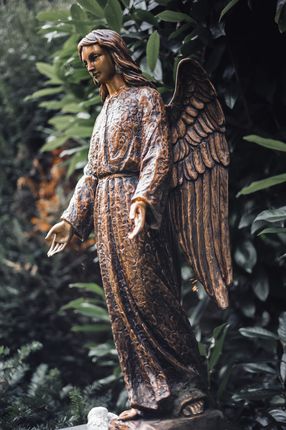 a statue of an angel standing in a garden