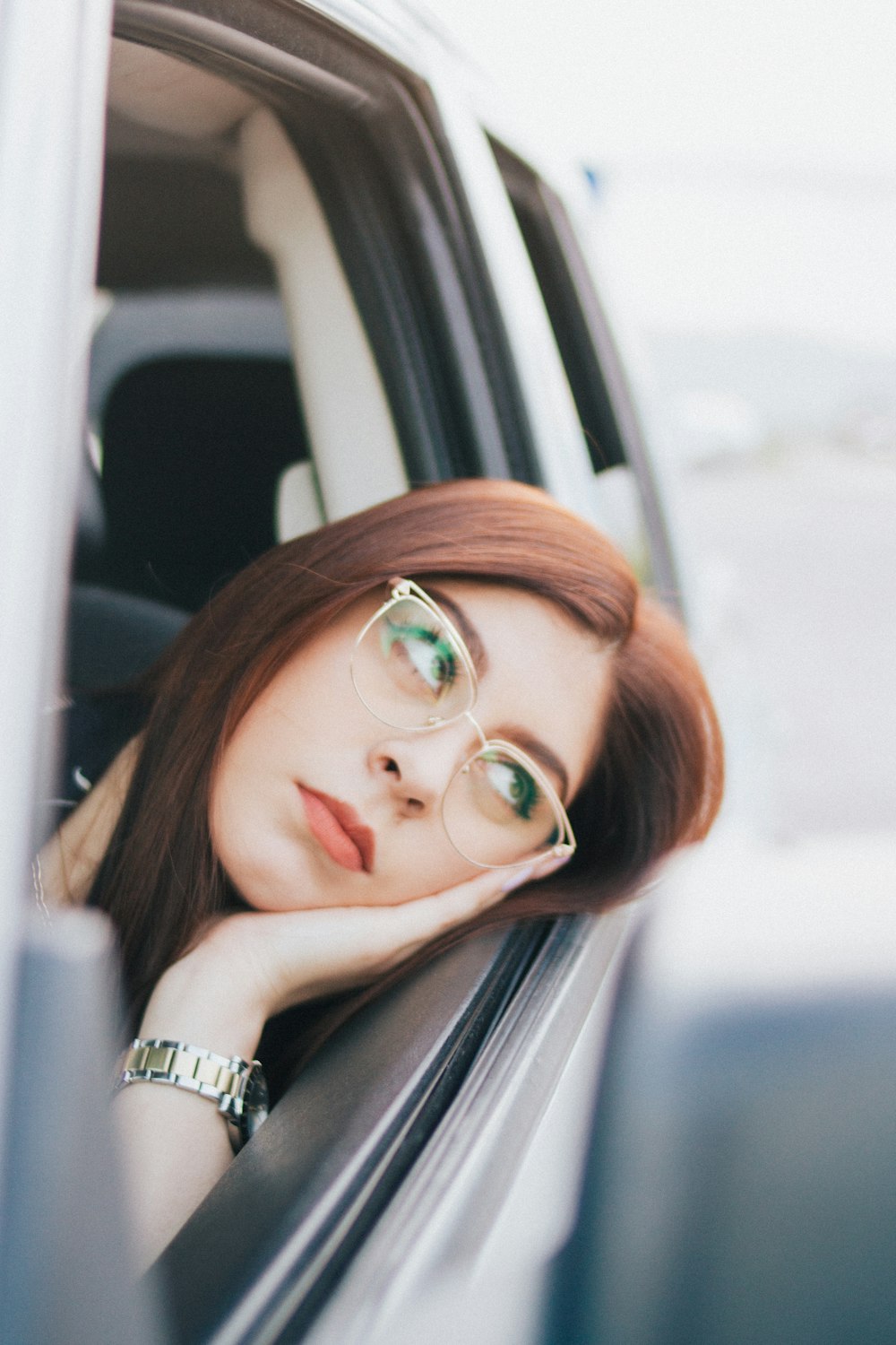 a woman with glasses sitting in a car