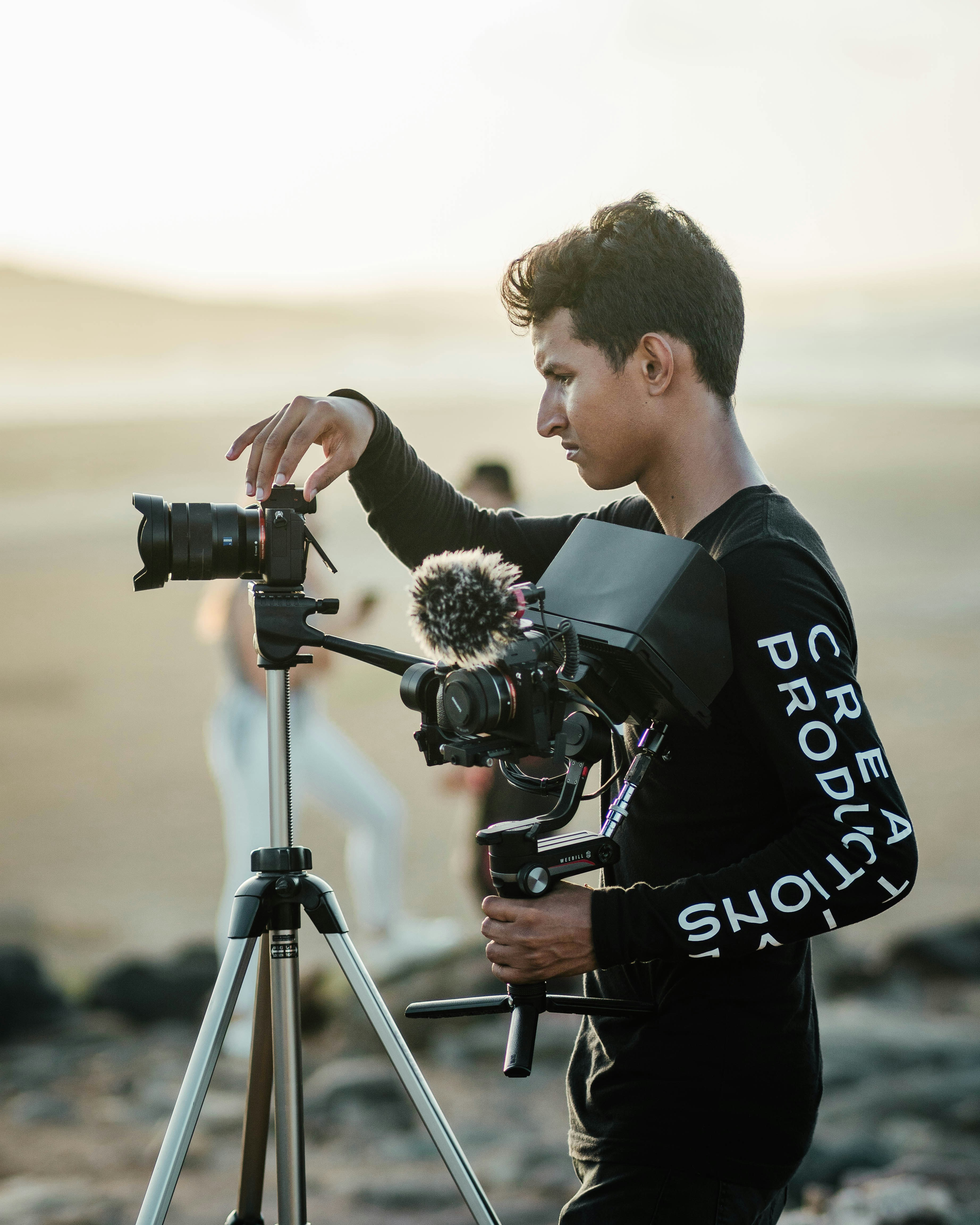 a man holding a camera next to a tripod