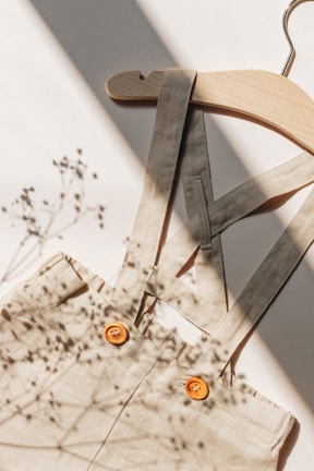 An elegant silk blouse draping softly over a wooden hanger in natural light.