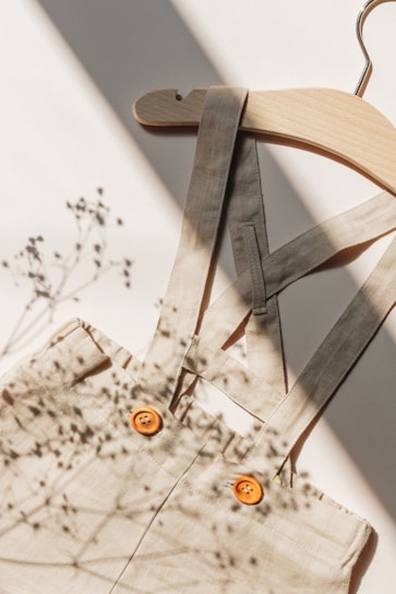 Close-up of a stylish blouse with delicate details, draped on a wooden hanger in soft natural light.